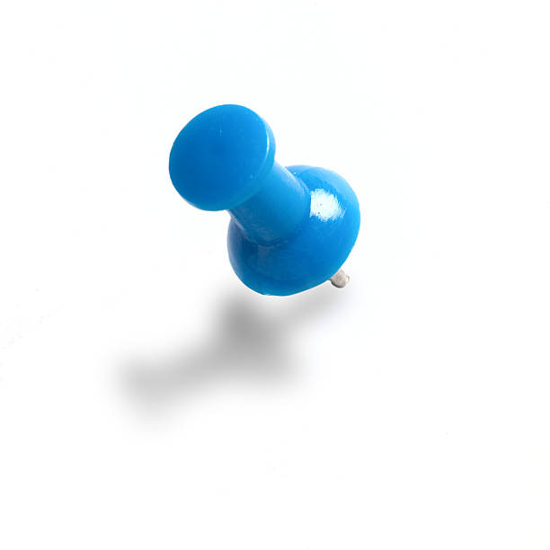 A blue push pin on a white wall stock photo