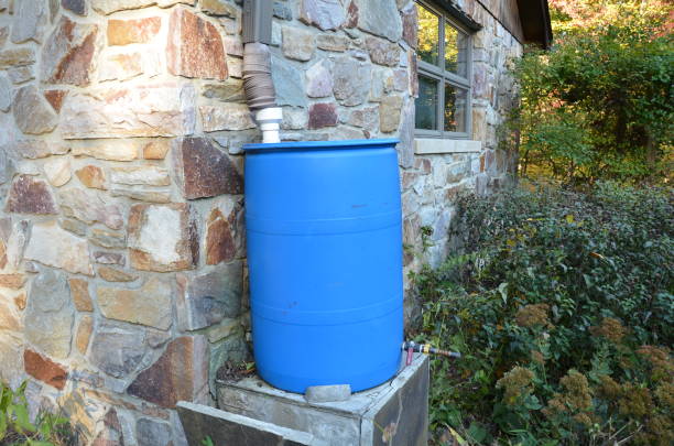 blue rain barrel with downspout and stone building stock photo