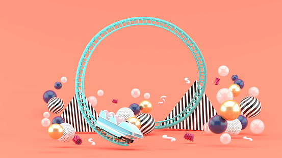 A blue roller coaster among colorful balls on a pink background.-3d rendering.