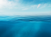 Blue sea or ocean water surface and underwater with sunny and cloudy sky.
