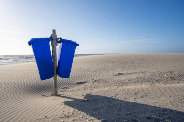 blue trash cans on an empty and deserted sandy beach. stock photo