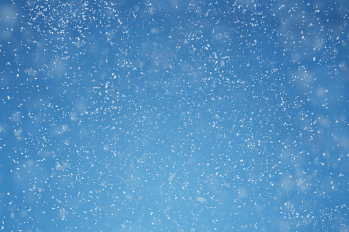 Falling snow over blue background with copy space