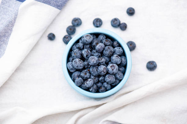 Blueberry or bilberry forest berries in blue ceramic plate on white tablecloth, top view Blueberry or bilberry forest berries in blue ceramic plate on white tablecloth, top view bilberry fruit stock pictures, royalty-free photos & images