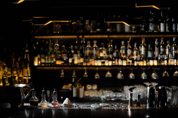 Blurred background of dark bar with barman essentials Blurred background of dark bar with bottles of alcohol and with barman essentials in the foreground bar counter stock pictures, royalty-free photos & images