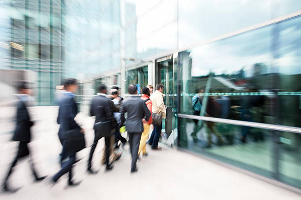 blurred business people entering office building through glass doors - betreden stockfoto's en -beelden
