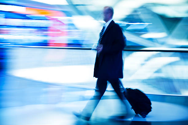 un flou homme d'affaires tirant valise au intérieur moderne - night lugage photos et images de collection