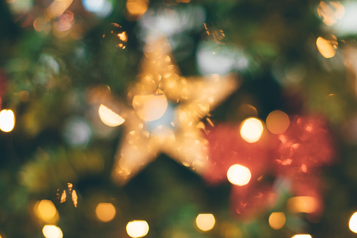 Blurred Christmas tree, lights decorations and a gold star, background