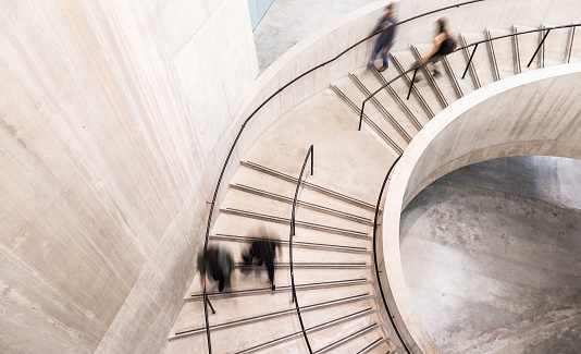 Spiral staircase with people walking down with motion blur.