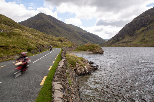 Blurred motorcycle on the road R335, on the lakeside of Doo Lough, with Ben Gorm in the background, County Mayo, Ireland