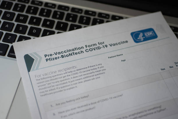 Blurred Pre-Vaccination Form for Pfizer-BioNTech COVID-19 Vaccine by CDC on laptop keyboard Washington, DC, USA - December, 23, 2020: Blurred Pre-Vaccination Form for Pfizer-BioNTech COVID-19 Vaccine by CDC on laptop keyboard cdc vaccine card stock pictures, royalty-free photos & images