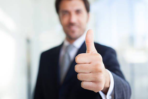 A blurry image of a businessman giving a clear thumbs up stock photo