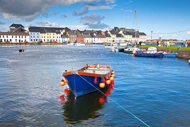 Boat In Galway Bay, Ireland Boat in Galway Bay in front of old Galway Town and it's pastel buildings. connemara stock pictures, royalty-free photos & images