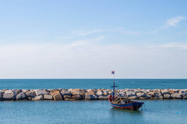 boat next to the stone embankment in the blue sea stock photo