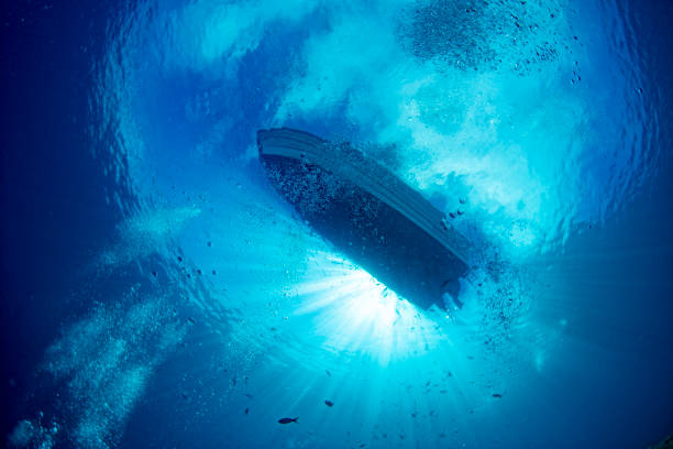boat ship from underwater blue ocean with sun rays stock photo
