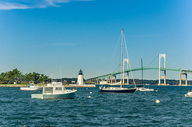 Boats Moored in Harbour and a Lighthouse Boats in Newport harbour with a Lighthouse and the bridge in background, Rhode Island. newport rhode island stock pictures, royalty-free photos & images