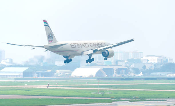 boeing 777 frachtflugzeuge von etihad fliegen über den himmel, um auf dem tan son nhat international airport landen - etihad airways stock-fotos und bilder