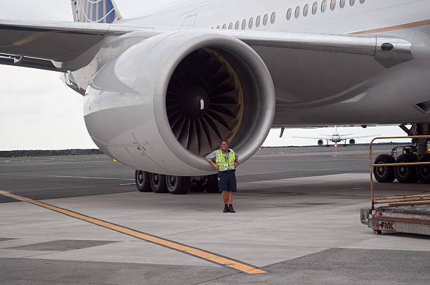 Boeing 777 Engine "Kailua Kona, HI, USA - February 19, 2011: An airport worker stands in front of a Boeing 777 engine showing the massive size on the tarmac of the Keahole International Airport." neicebird stock pictures, royalty-free photos & images