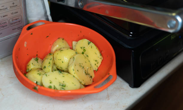 boiled potatoes sprinkled with dill lie in a plastic bowl stock photo