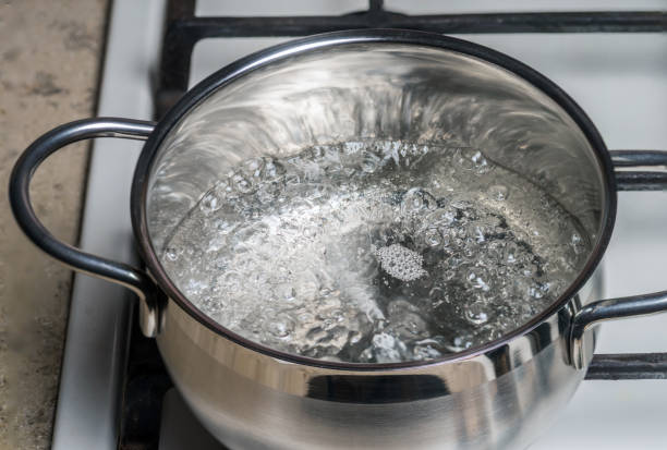 Boiling water in a stainless saucepan on a gas stock photo