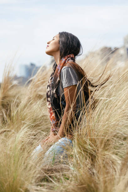 ragazza boliviana seduta sull'erba alta guardando il cielo - correa foto e immagini stock