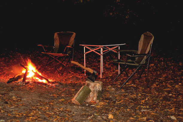 焚き火の夜のグレードキャンプ家具、観光キャンプ、薪や斧のクローズアップ - wood table ストックフォトと画像
