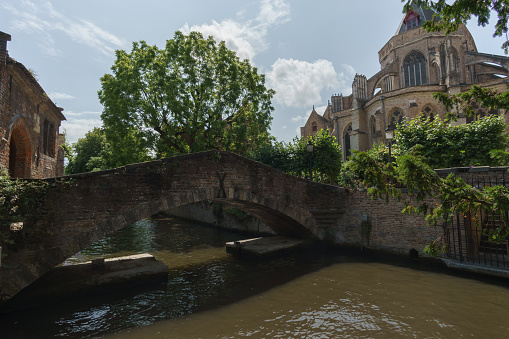 Bonifazius Bridge over water canal with trees and Church of Our Lady, Bruges, Belgium