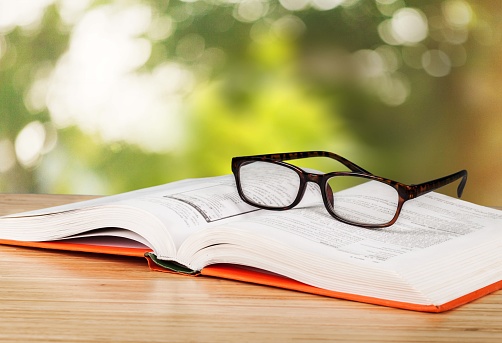 Close-up view of open book and eyeglasses
