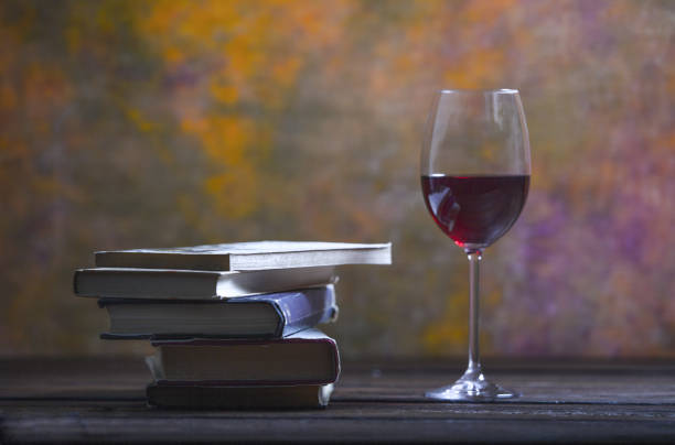 Books and a glass of wine Glass of red wine next to a pile of books romance book cover stock pictures, royalty-free photos & images