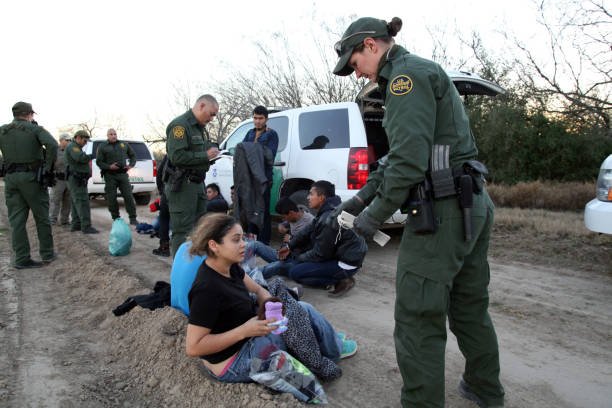 Border Patrol, Rio Grande Valley, Texas, Feb. 9, 2016 Fronton, Texas, USA - February 9, 2016: A young Salvadoran woman being taken into custody for illegally entering the United States by crossing the Rio Grande River in deep south Texas hands some of her belongings to a female Border Patrol agent. Young Central Americans, most fleeing gang violence and poverty, continue to illegally enter the U.S. at near record levels. border patrol stock pictures, royalty-free photos & images