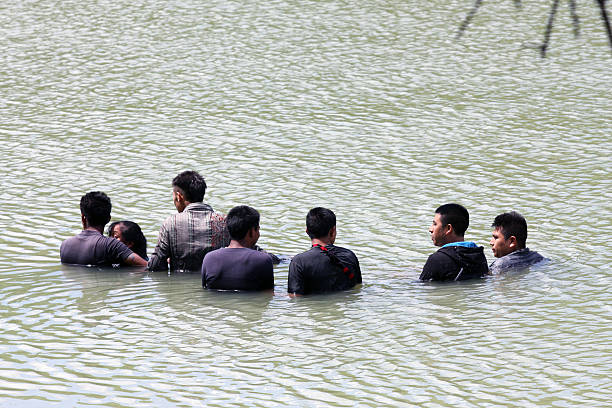 Border Patrol, Rio Grande Valley, Texas, Sept. 21, 2015 La Grulla, Texas, USA - September 21, 2015: A group of young unaccompanied Central Americans wait for a raft to pick them up and return them to Mexico from the Rio Grande River after being discovered attempting to enter the United States illegally by the Border Patrol. There was a marked increase in the number of unaccompanied Central American juveniles attempting to enter the U.S. illegally over the summer. border patrol stock pictures, royalty-free photos & images