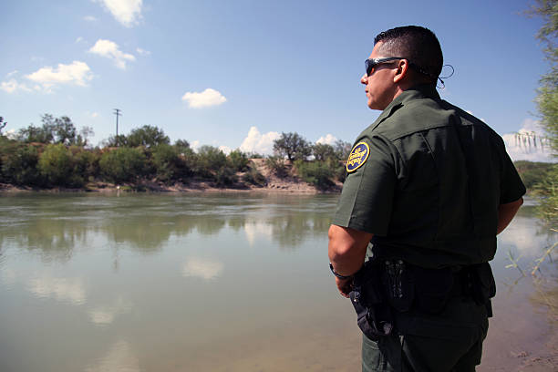 Border Patrol, Rio Grande Valley, Texas, Sept. 21, 2016 McAllen, Texas, USA - September 21, 2016:  A Border Patrol agent looks at Mexico across the Rio Grande River in deep south Texas. There has been a flood of mothers with children and unaccompanied minors from Central America fleeing gang violence crossing illegally over the past several months. border patrol stock pictures, royalty-free photos & images