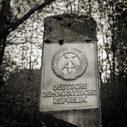 Braunlage, Germany - April 29, 2018: Border pillar of the former inner German border with the emblem of the GDR in the forest in the Harz National Park in Germany