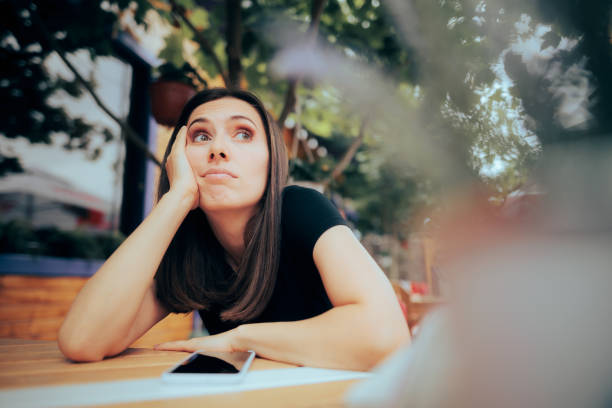 Bored Woman Waiting a Phone Call in a Restaurant Lonely woman feeling depressed and disappointed after a cellphone breakup fomo stock pictures, royalty-free photos & images