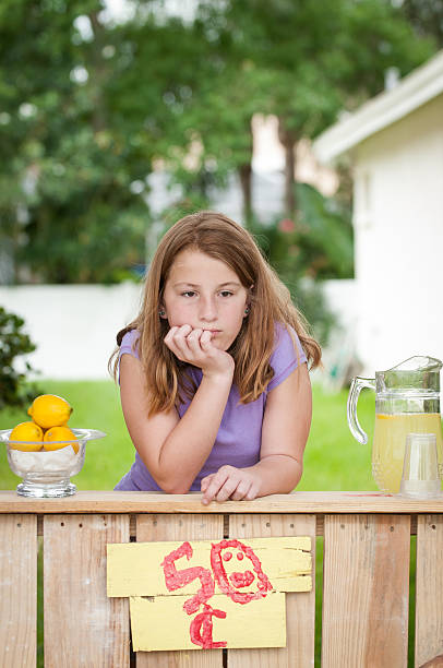 Bored young girl with no customers at her lemonade stand stock photo