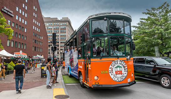 Boston Massachusetts, United States - August 4, 2021: Trolley tour bus with stop at the New England Aquarium, full of tourists. This private company trolley service combines history, fun facts, colorful anecdotes, and service to provide their guests with a memorable vacation experience.