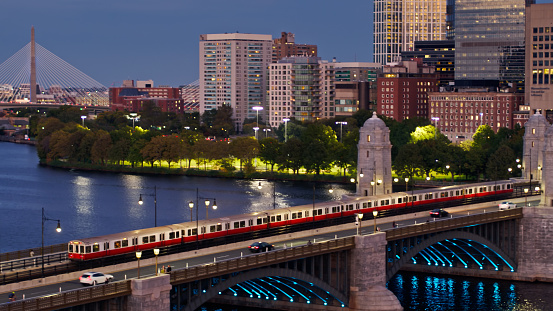 Drone shot of subway train on Longfellow Bridge in Boston at twilight, with Massachusetts General Hospital, Lederman Park and Zakim Bridge in background. \n\nAuthorization was obtained from the FAA for this operation in restricted airspace.