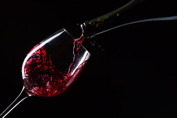 bottle and glass with red wine on a black background