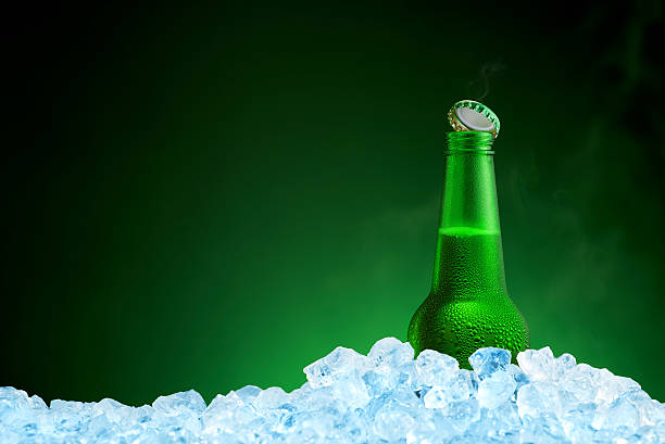 Bottle of cold beer in ice on green background stock photo