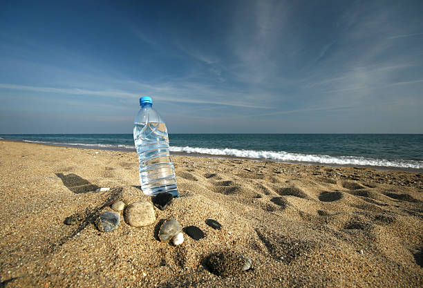bottle of fresh cool water on a sand beach stock photo