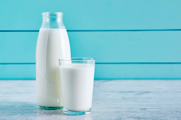 fles melk en een glas vol melk op een houten tafel tegen turquoise houten achtergrond. close-up te bekijken. - melk stockfoto's en -beelden