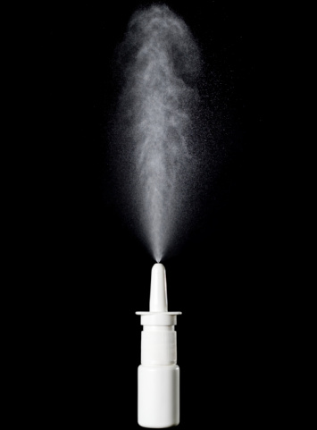 Anti sniffle concept, nasal spray bottle while spraying isolated on  black background.