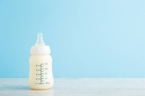 Bottle of white milk on wooden table at light blue wall background. Baby feeding concept. Pastel color. Closeup. Empty place for text. Front view. Bottle of white milk on wooden table at light blue wall background. Baby feeding concept. Pastel color. Closeup. Empty place for text. Front view. baby formula stock pictures, royalty-free photos & images