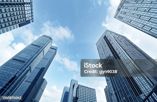 istock Bottom view of modern skyscrapers in business district against blue sky 1340874042