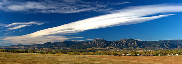 Boulder Flatirons in the Fall A panoramic view of the Boulder Flatirons in the Fall. The shot includes some gorgeous golden colors characteristic of the Colorado fall as well as an amazing cloud formation right above the mountains.  boulder colorado stock pictures, royalty-free photos & images