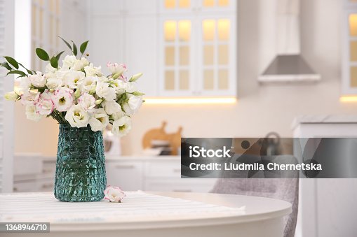 istock Bouquet of beautiful flowers on table in kitchen, space for text. Interior design 1368946710