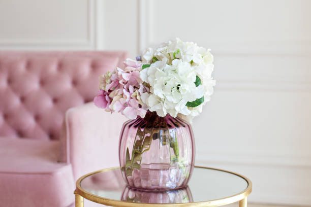 Bouquet of pastel hydrangeas in glass vase. Flowers in a vase at home. beautiful bouquet of hydrangeas is in a vase on a table near a pink sofa in a white living room. Home interior decor. Scandinavia Bouquet of pastel hydrangeas in glass vase. Flowers in a vase at home. beautiful bouquet of hydrangeas is in a vase on a table near a pink sofa in a white living room. Home interior decor. Scandinavia hydrangea stock pictures, royalty-free photos & images