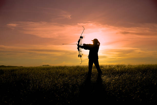 Bowhunter at Sunset a bowhunter silhouetted against a brilliant sunset hunting sport stock pictures, royalty-free photos & images