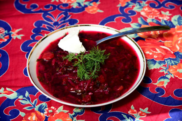 A bowl of borscht garnished with dill and a dollop of smetana (sour cream) stock photo