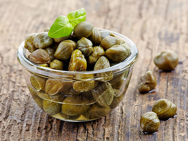 bowl of capers bowl of capers on wooden table caper stock pictures, royalty-free photos & images