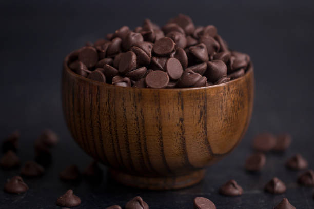 A Bowl of Chocolate Chips on a Slate Countertop A Bowl of Chocolate Chips on a Slate Countertop semi sweet chocolate stock pictures, royalty-free photos & images